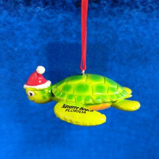 Sea turtle ornament made from durable rubber. Bright green on the shell that fades to yellow on bottom. Wearing a Santa Hat on head. Navarre Beach Florida is painted on the front left flipper.